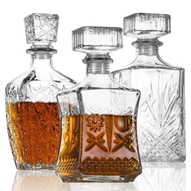 Three crystal decanters, two filled with amber liquid, on a white background